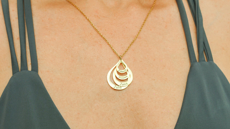 Woman wearing a green bikini top with a gold necklace featuring a teardrop pendant.